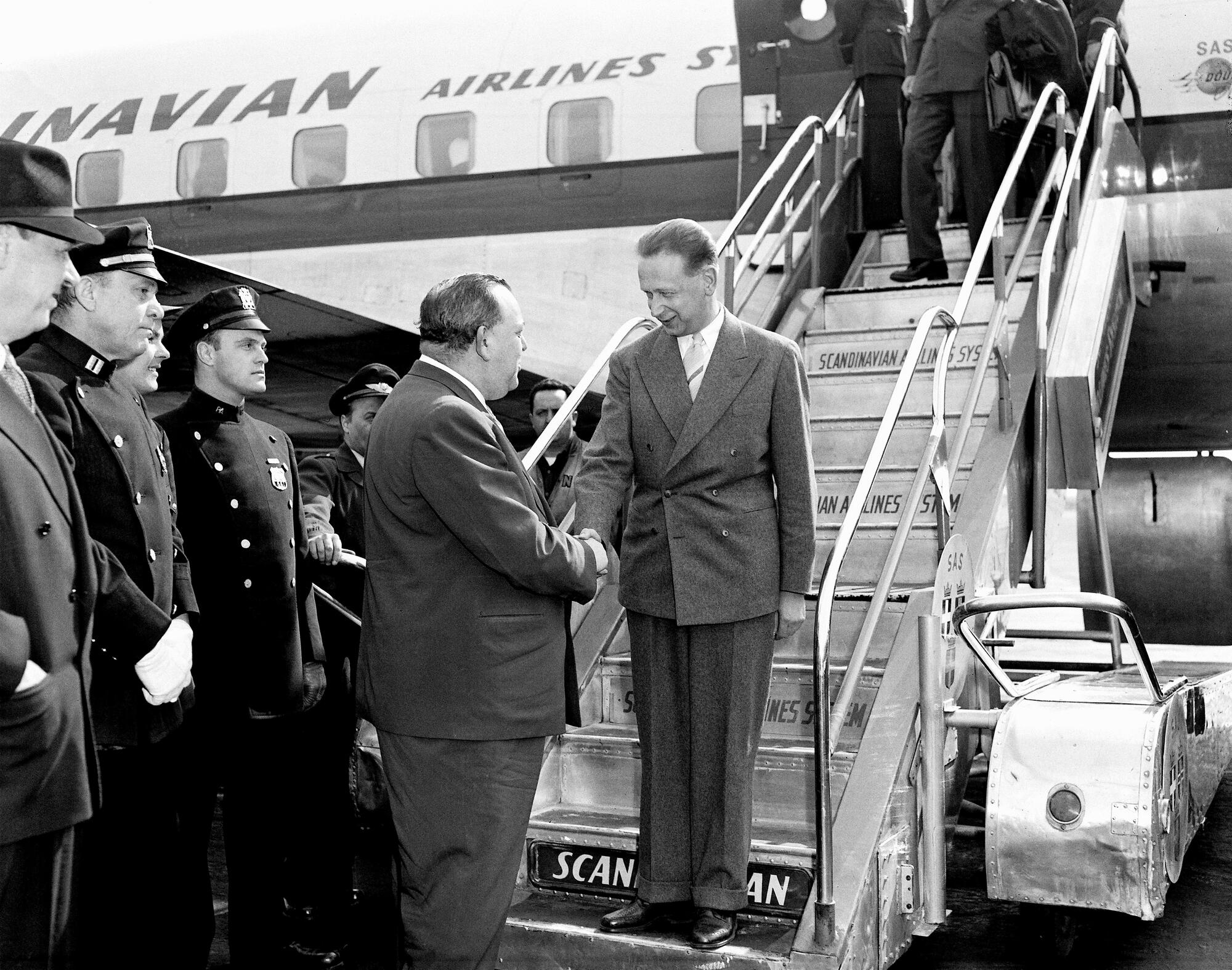 The new Secretary-General designate of the United Nations, Dag Hammarskjöld (right) of Sweden, arrived in New York by air from Stockholm today. He will be inducted tomorrow afternoon at a ceremony to be held before the General Assembly. Here, at Idlewild Airport, Secretary-General Trygve Lie welcomes his successor as he was alighting from the plane.